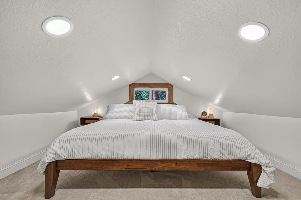 Cozy loft bedroom with king bed, warm wood accents, and soft recessed lighting