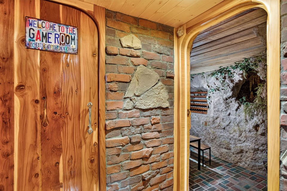Fun game room entry with rustic brick details and a unique grotto-style hangout space beyond.