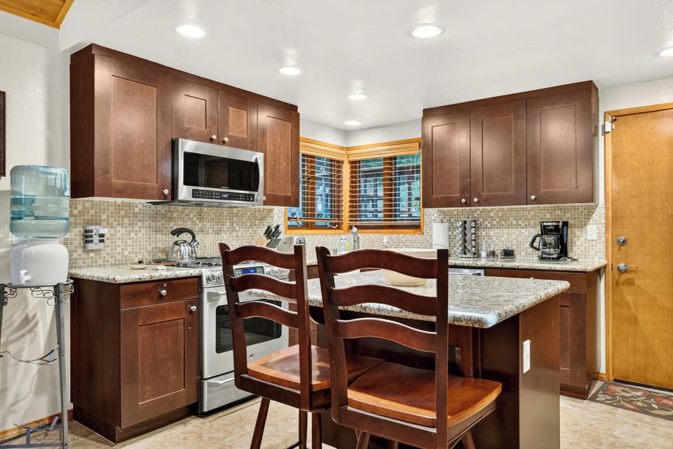 Kitchen and dining area with island seating, stainless steel appliances, and easy access to the upper level.