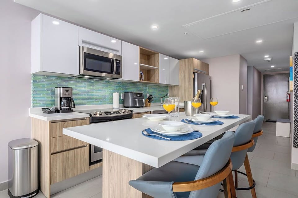 Picture yourself gathering around this sleek island, preparing fresh meals in your fully-equipped kitchen, complete with modern appliances and cheerful touches. The bright, inviting space makes every breakfast feel special.