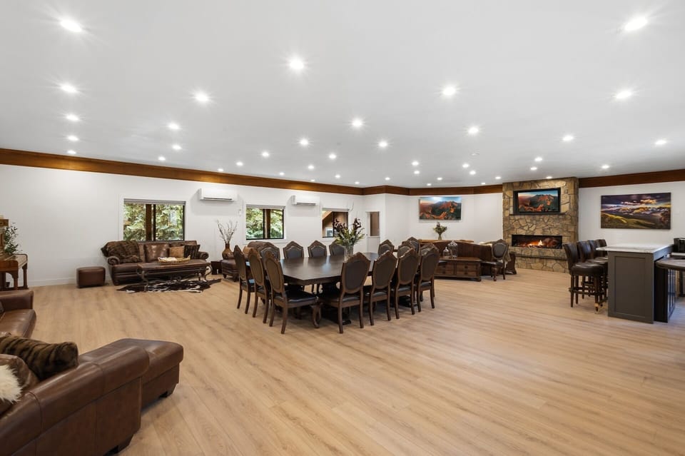 Great Room - Great room with large fireplace, smart TV, dining space for 14 people, lounging areas, antique piano, and bar.