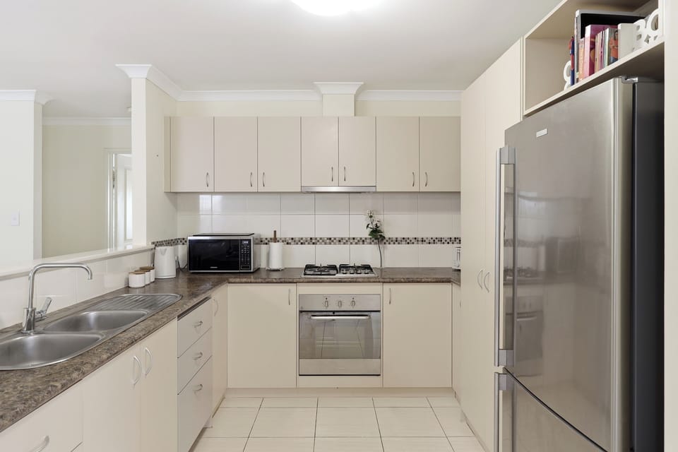 Modern, spotless, and fully equipped with stainless steel appliances (fridge, stove, oven, microwave) and a spacious double sink.