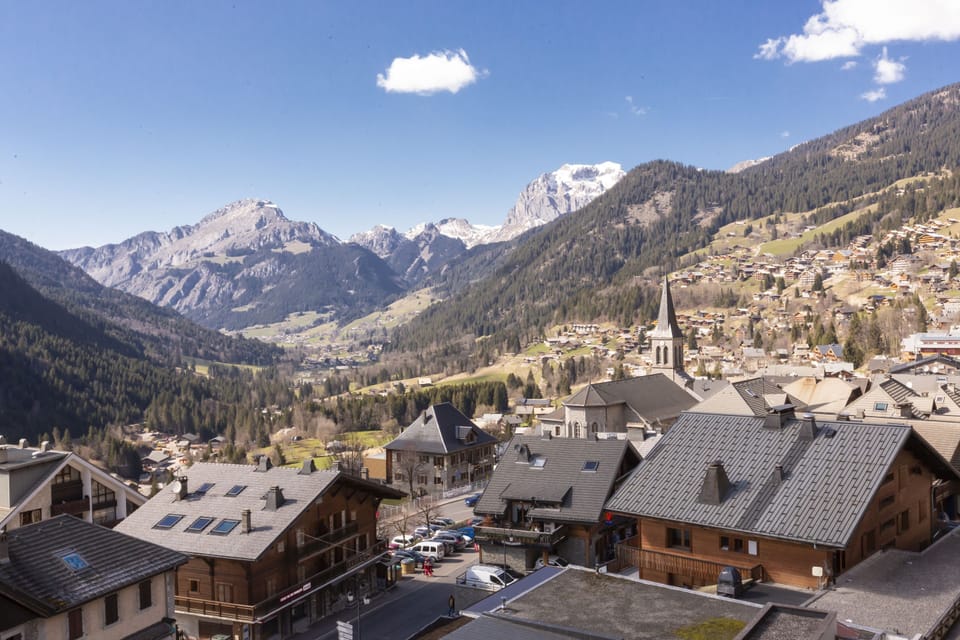 A balcony view across Châtel's rooftops and valley — the church steeple of the village visible in the distance.