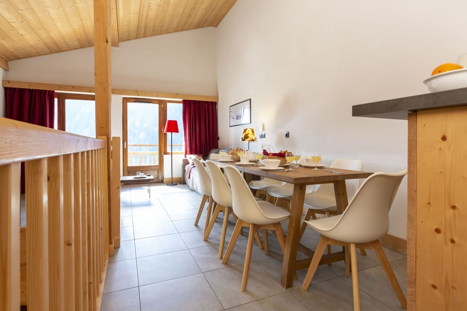 The dining table set for the group, with the mountain light coming through the red-curtained windows.
