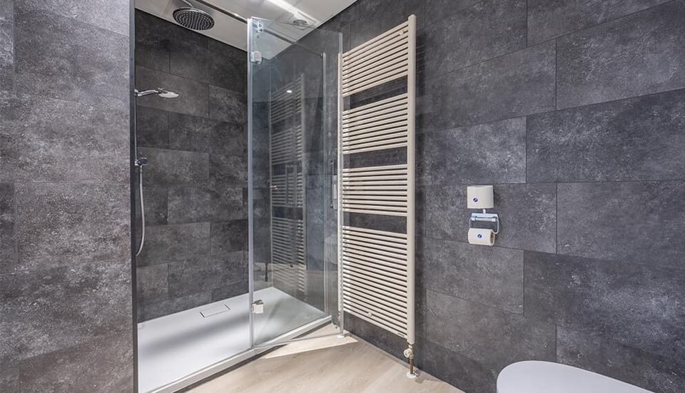 Refresh under a rainfall shower in sleek stone surroundings.
