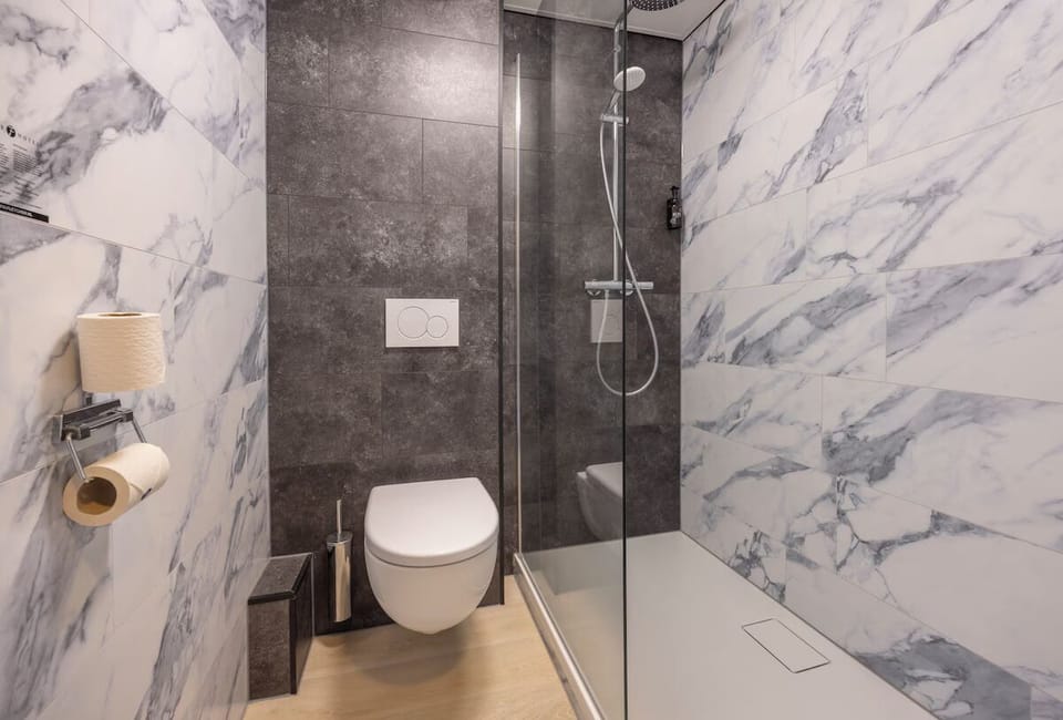 Refresh under a sleek walk-in shower in marble style.