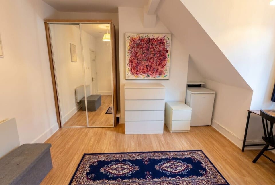 Spacious attic room with mirrored wardrobe and abstract statement art.