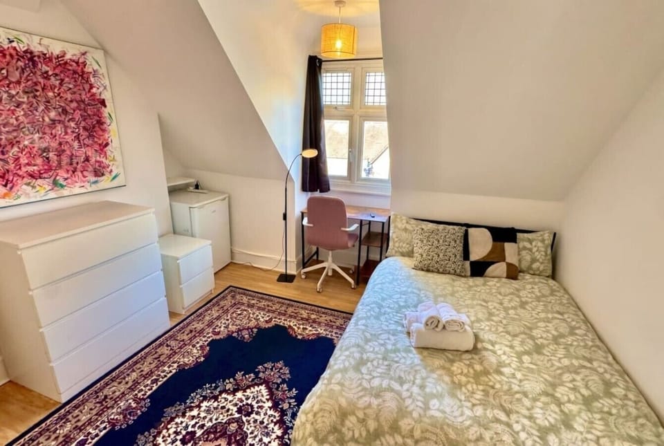 Sunny attic single with window desk, statement art and towels ready.