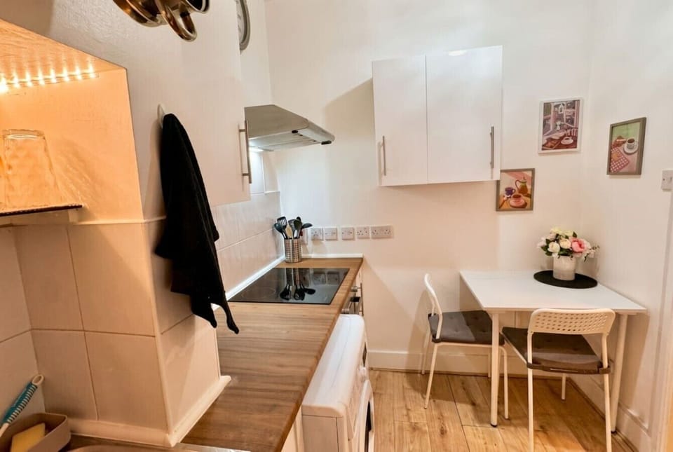 Compact kitchen with hob, oven and a sunny two-seat dining spot.