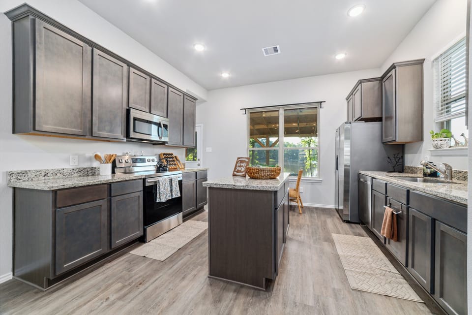 Bright modern kitchen with granite counters, island, and stainless appliances
