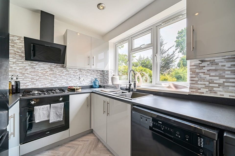 Sleek kitchen with dishwasher and leafy garden views right over the sink
