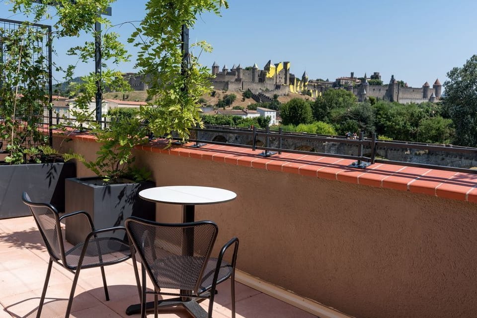 Private terrace with table and chairs overlooking the Cité Médiévale — included with Deluxe rooms.
