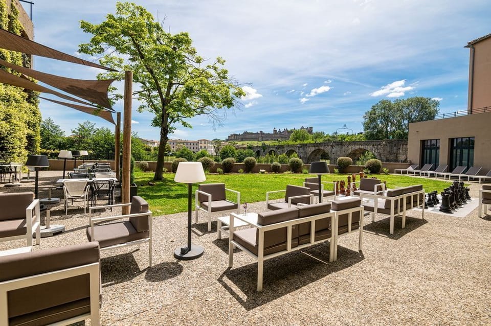 Dine al fresco under white shade sails surrounded by trees, 100 metres from Carcassonne's walled city.