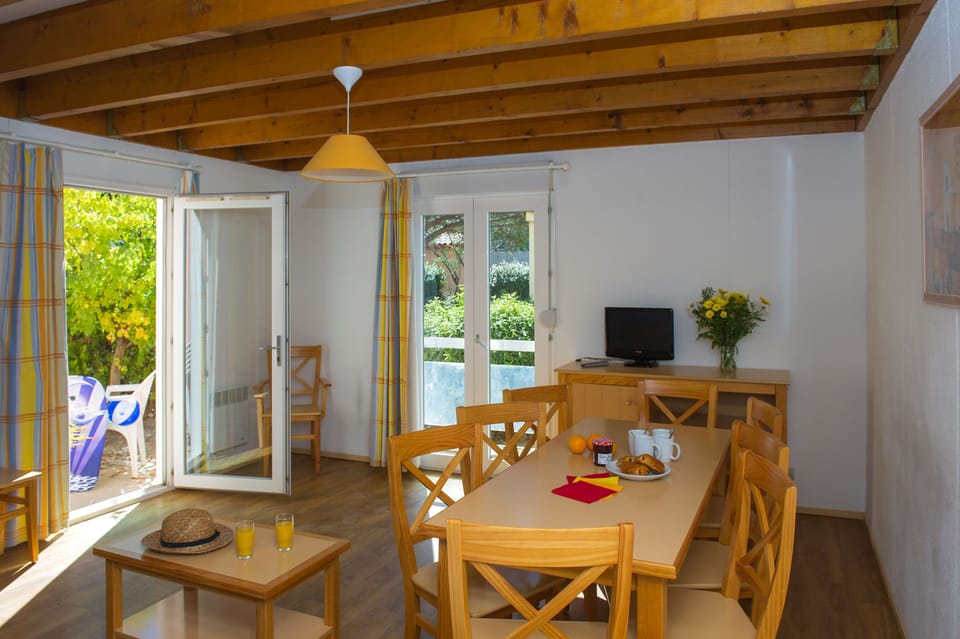 The bright dining area with warm wooden beams and direct access to the private terrace.