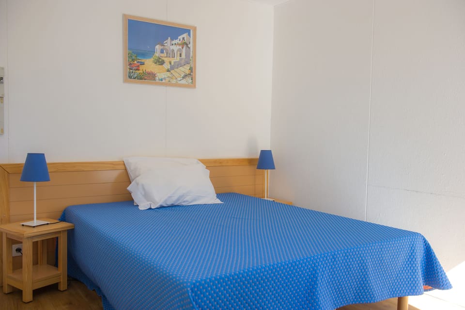 A restful double bedroom with warm wooden furniture and a calming Mediterranean colour palette.