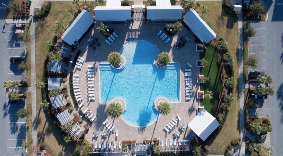 Resort-style pool oasis with cabanas, loungers, and sunny palm-lined spaces