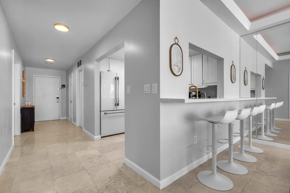 Sleek breakfast bar with seating for four, flowing into a full kitchen with modern appliances. Perfect for casual meals and morning coffee before hitting the beach.