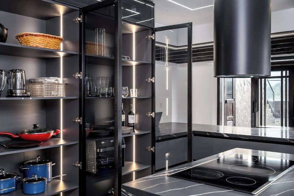 Fully equipped kitchen with a central island, induction stove, oven, microwave, refrigerator, washing machine, and large windows overlooking the city. A modern, comfortable, and functional space to enjoy during your stay.