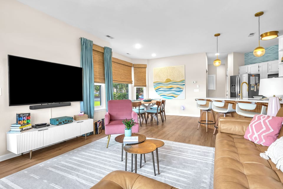 Bright open living room with big TV, dining space, and modern kitchen