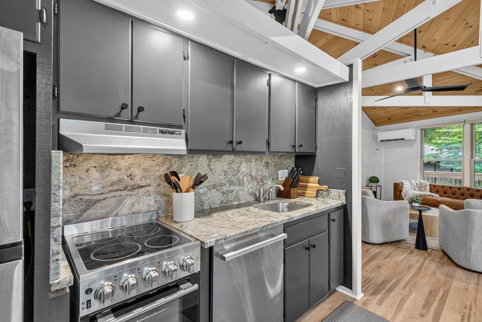 A fully equipped kitchen with granite counters and gray cabinets, flowing right into the cozy living space at Birdie Bungalow.