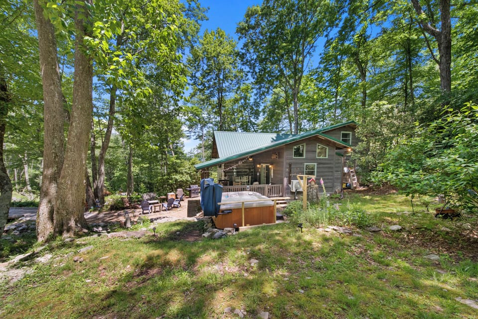 Creekside Cottage and its outdoor living spaces tucked among mature hardwood trees