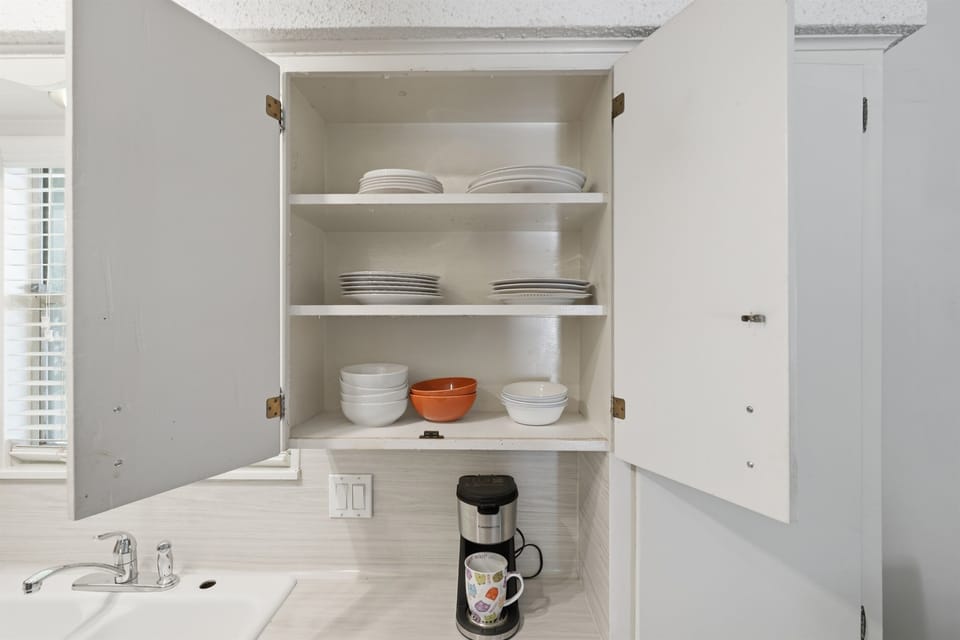 Bright and functional kitchen stocked with cookware, dishes, and cooking essentials.