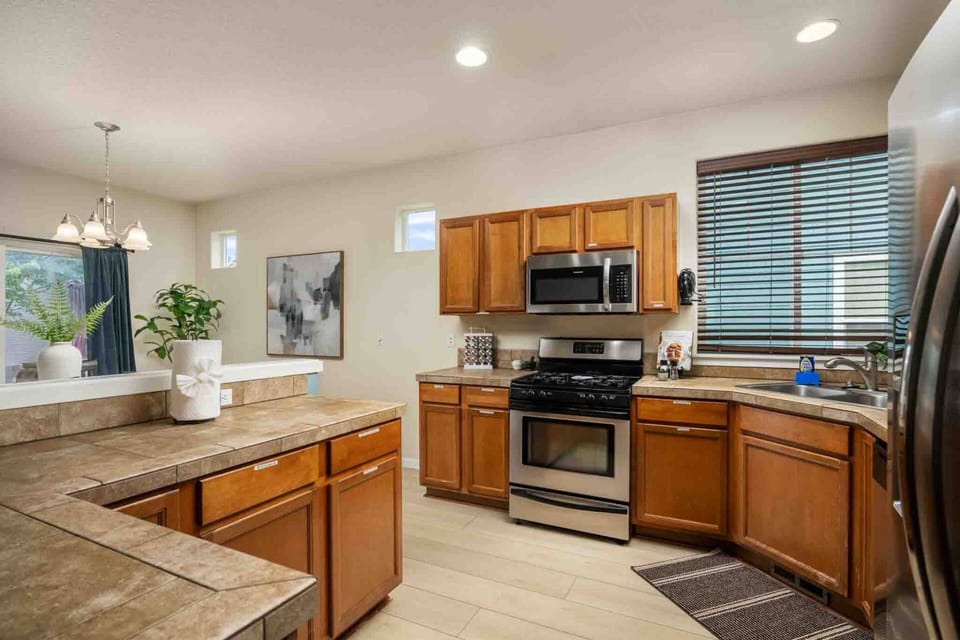 An alternate angle of the kitchen showing the built-in microwave, gas range stove, corner sink with window views, and ample cabinet storage.