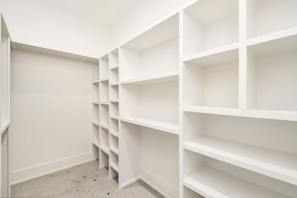 Spacious walk-in storage room with custom built-in shelving