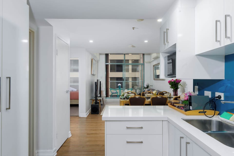 Sleek, fully equipped kitchen with crisp white cabinetry and generous counter space. Bright and functional, it opens onto the living area and connects to the rest of the apartment for easy, everyday flow. 