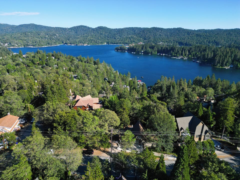 Aerial view of the property surrounded by lush forest and lake views.