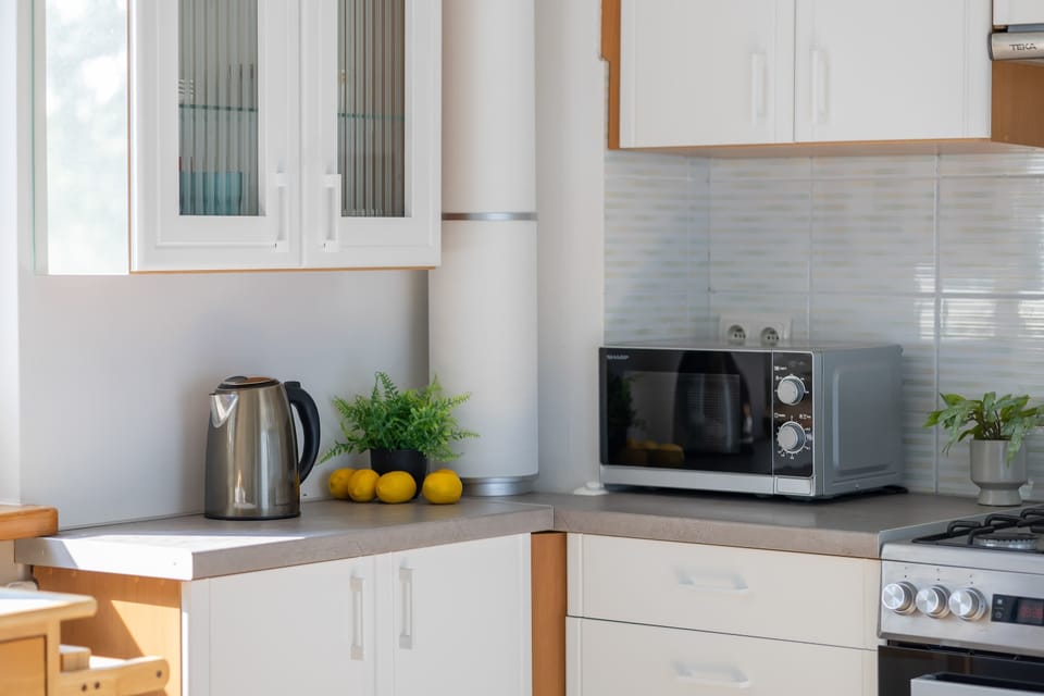 A close-up of the kitchen showcases a microwave, kettle, fruit bowl, and tidy worktops. Decorative touches make the cooking area feel homely.