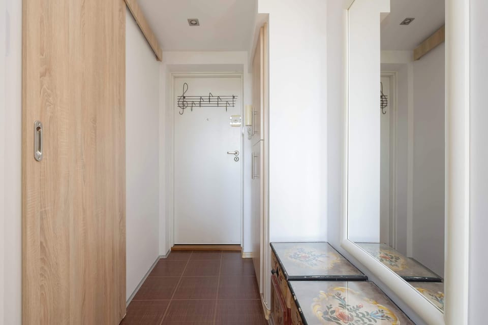 A hallway with built-in wardrobes leads from the entrance into the apartment. The corridor offers generous storage while maintaining a clean, modern appearance.
