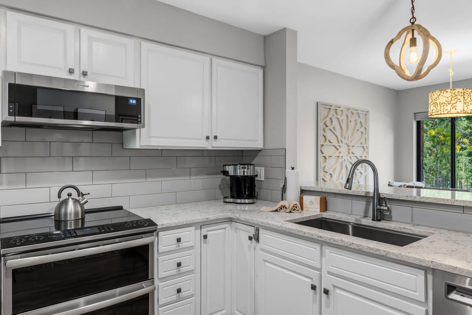 Step into your fully equipped kitchen, complete with stainless steel appliances, ample counter space, and a bright garden view—perfect for preparing your favorite meals at home.