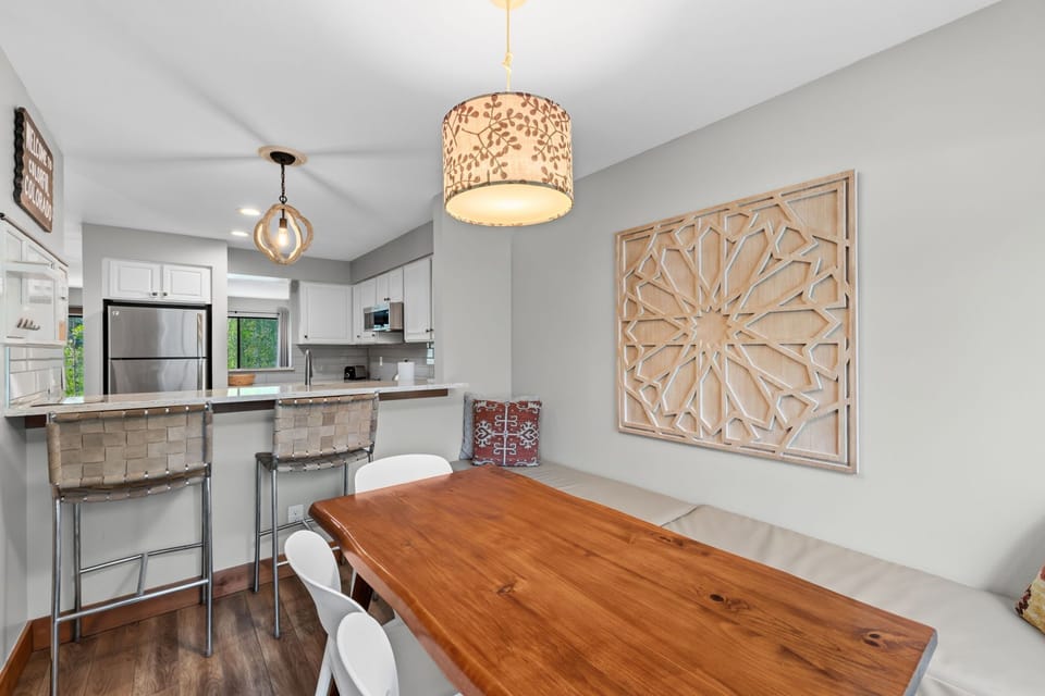 Gather around the warm wood table under soft pendant lighting, with your full kitchen just steps away for easy meal prep and morning coffee.
