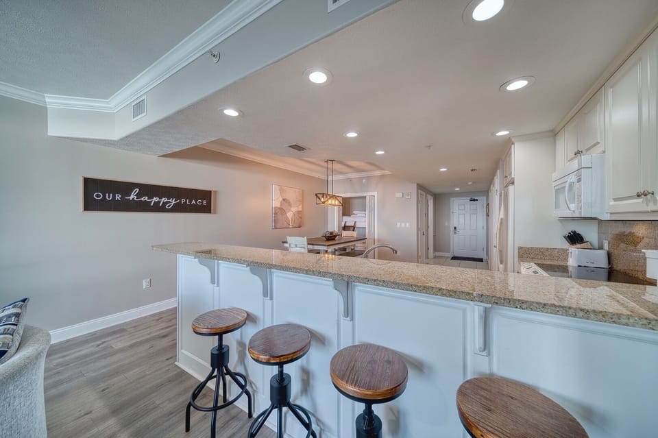 Your open-concept kitchen and living space welcomes you with a spacious breakfast bar, granite countertops, and coastal charm—perfect for gathering over morning coffee or evening conversations.