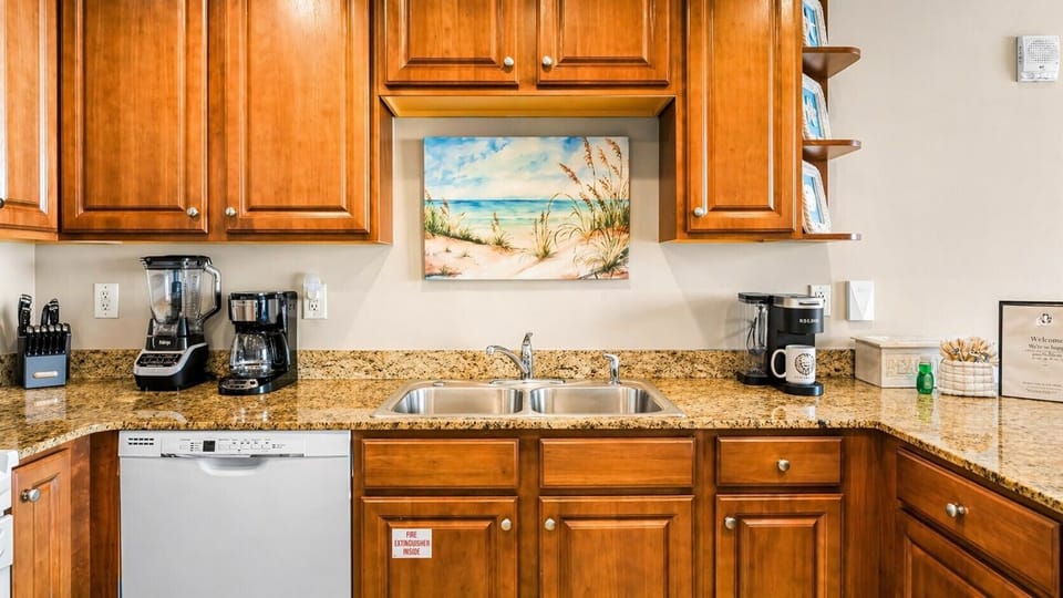 Your fully equipped kitchen features granite countertops, warm wood cabinetry, and modern appliances including a dishwasher, coffee maker, and blender for easy meal prep during your stay.