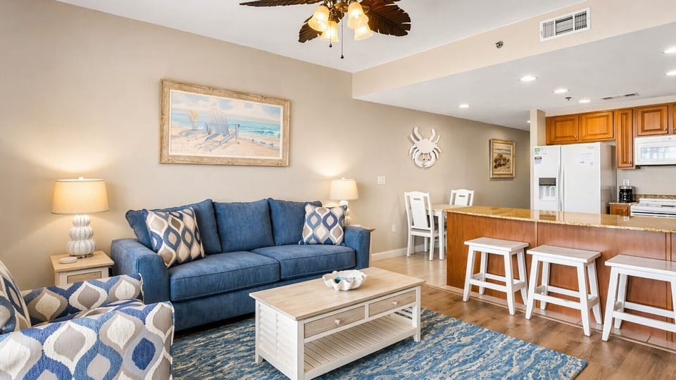 Unwind in your spacious living area with coastal-inspired decor and plush seating. The open-concept design flows into a well-equipped kitchen, perfect for preparing meals and gathering.