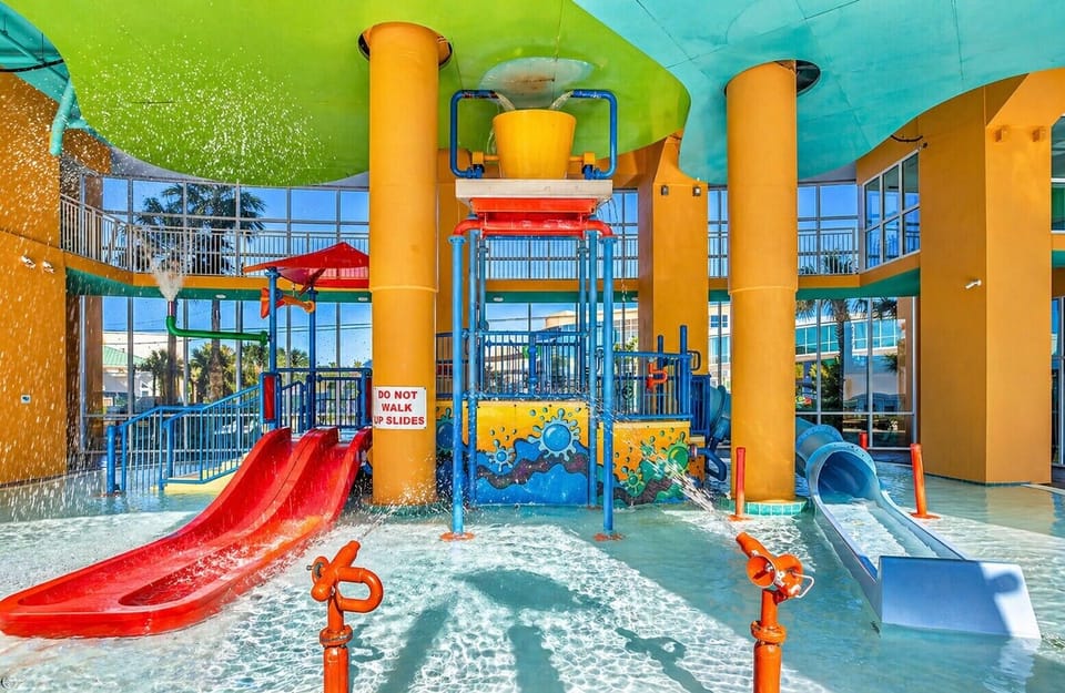 Indoor water playground with colorful slides, splash zones, and a giant tipping bucket overhead—perfect for keeping your little ones entertained for hours.