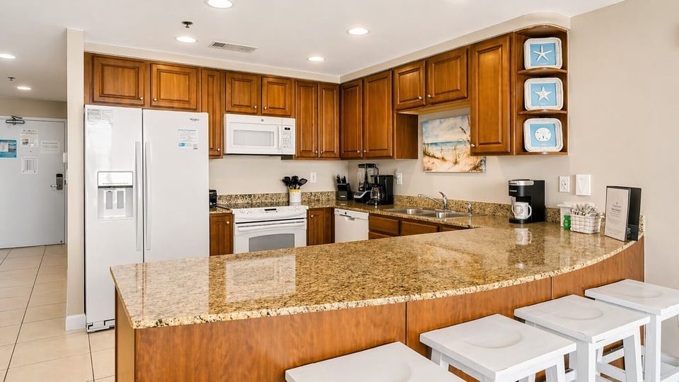 Step into your spacious, fully-equipped kitchen with granite countertops, modern appliances, and a breakfast bar—perfect for preparing meals and gathering with loved ones during your coastal getaway.