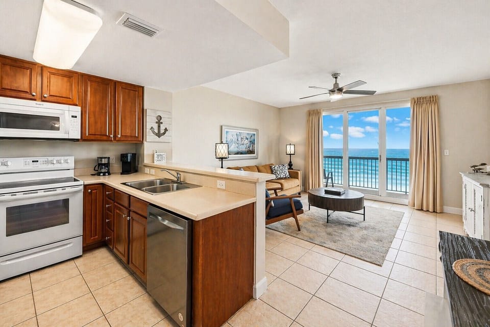Step into your oceanfront retreat where the kitchen flows seamlessly into your living space, framed by stunning sea views through floor-to-ceiling glass. Your private balcony invites you to sip morning coffee while waves greet the shore.