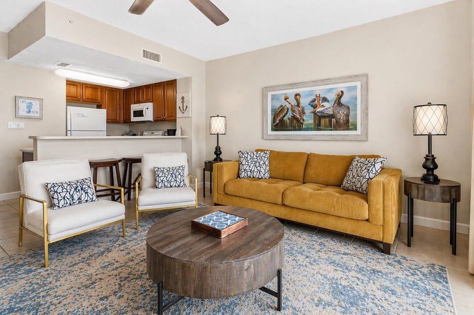 Unwind on your plush mustard sofa or gather around the coffee table in this inviting living area, complete with a fully equipped kitchen just steps away for easy meal prep.