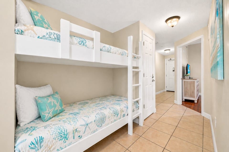 Your beachy bunk room awaits with coastal-themed bedding, crisp white built-in bunks, and cheerful turquoise accents that bring the ocean vibe right inside.