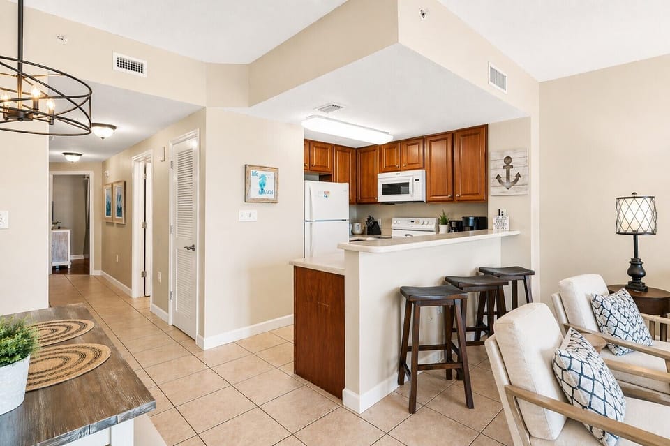 Gather around the breakfast bar in your open-concept kitchen, complete with warm wood cabinetry and modern appliances. The inviting layout flows into the dining and living spaces, creating the perfect setting for shared meals and cherished moments together