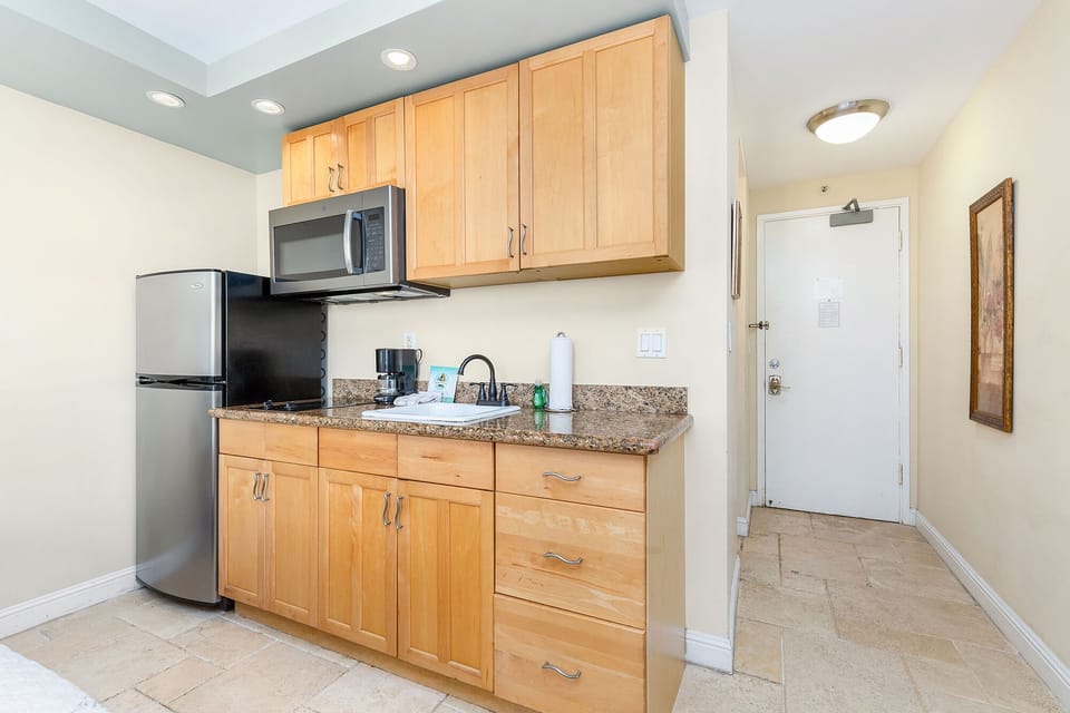 Your cozy kitchenette features warm wood cabinetry, granite counters, and modern appliances—perfect for preparing simple meals at your leisure.