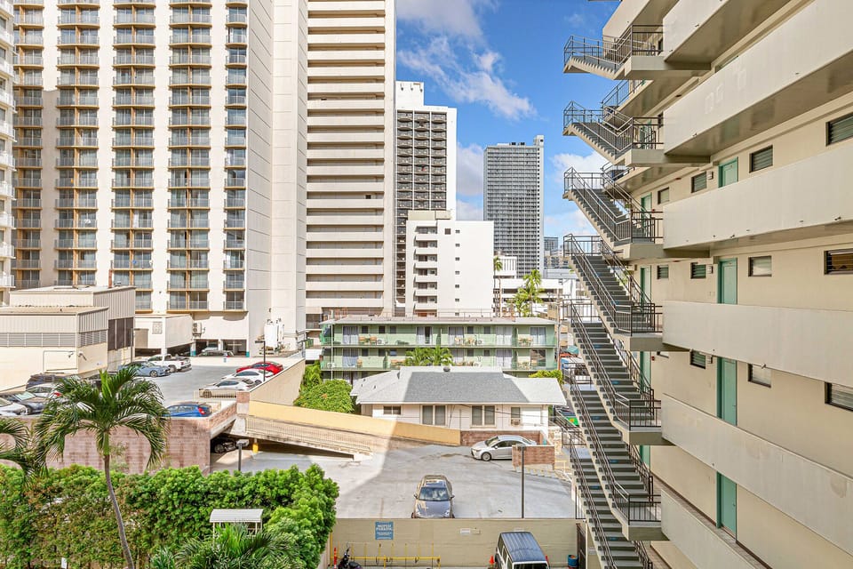 Urban cityscape with high-rise towers, parking area, and nearby buildings characteristic of the surrounding neighborhood.