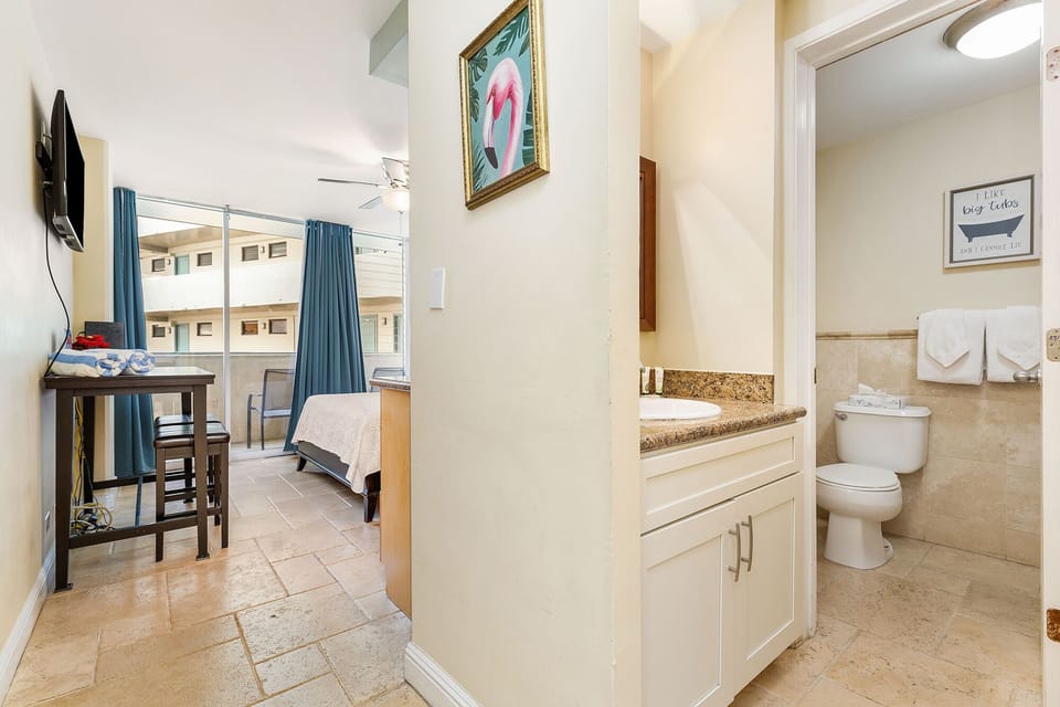 Your cozy suite flows seamlessly from bedroom to bath, with playful coastal art, thoughtful amenities, and a private balcony that brings warmth and comfort to every moment of your stay.