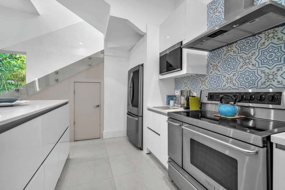Sleek, fully equipped kitchen featuring a spacious center island with bar seating for four, stainless steel appliances, and a built-in wine cooler