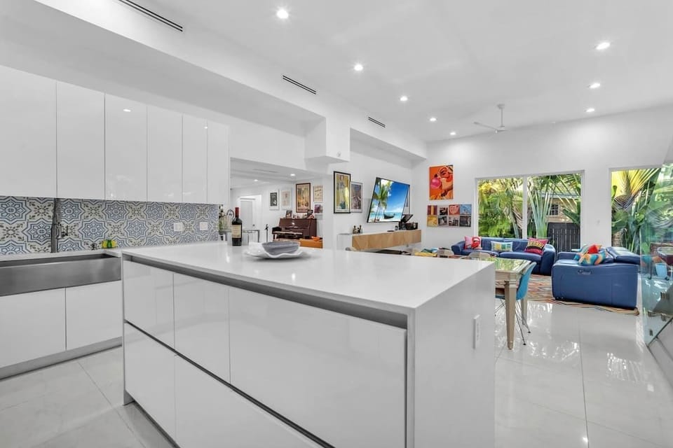Sleek, fully equipped kitchen featuring a spacious center island with bar seating for four, stainless steel appliances, and a built-in wine cooler