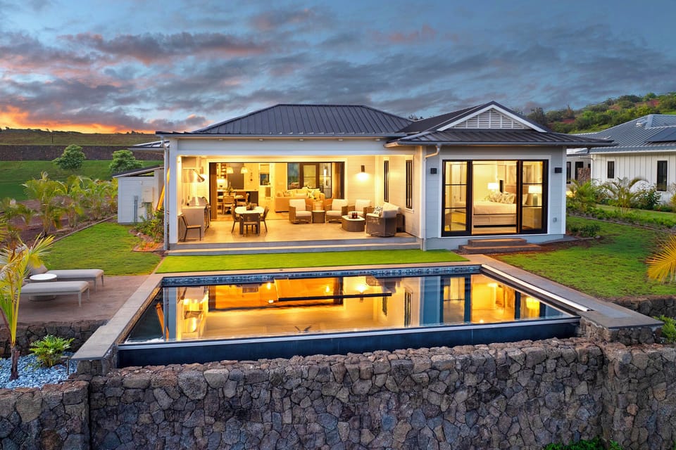 As the light fades, the home glows above its ocean-view pool on Kauai's South Shore.