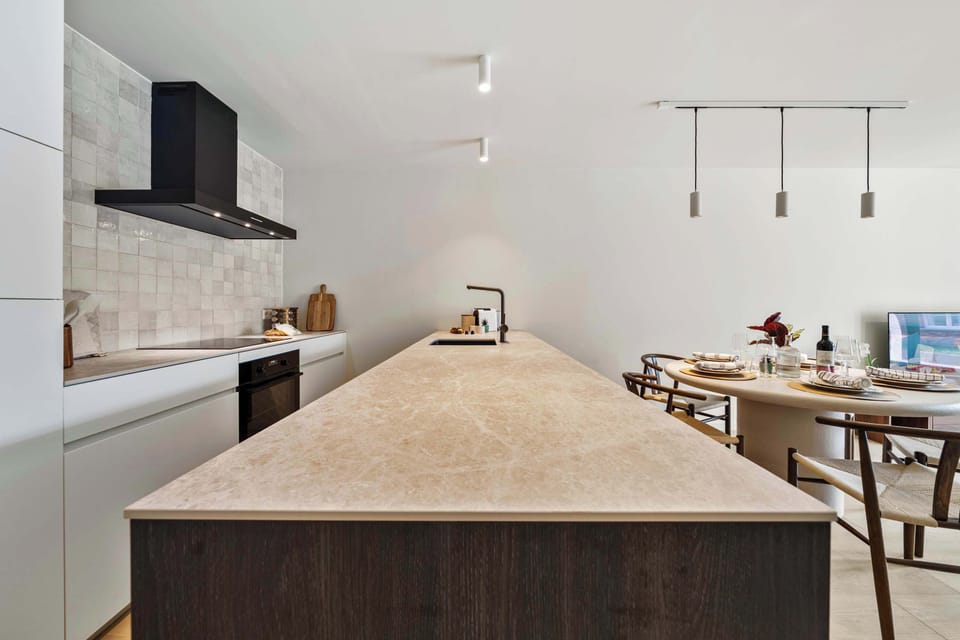 Spacious kitchen with a large central island, breakfast bar seating and pendant lighting in this luxury 2-bedroom holiday apartment in De Haan, your stylish home base near the North Sea beach on the Belgian coast.
